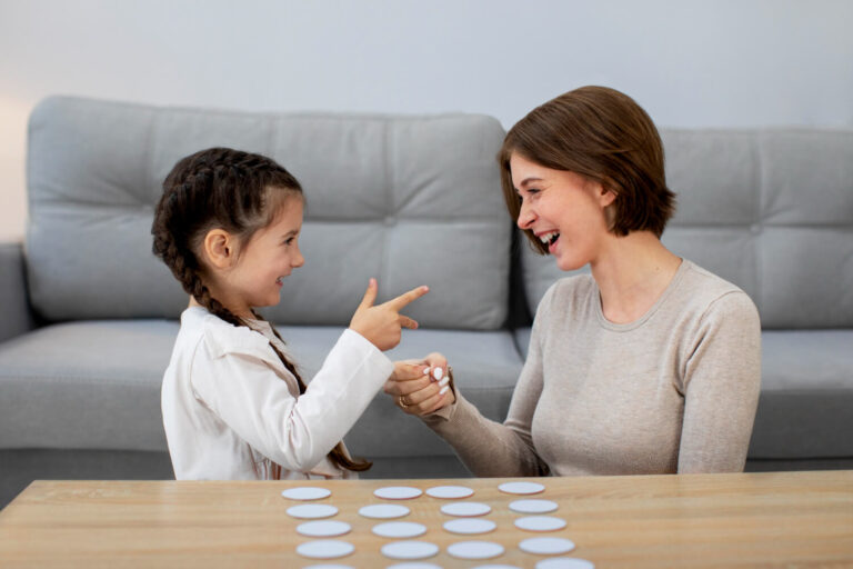 Psicóloga interage sorrindo com menina durante dinâmica com cartas na avaliação psicológica infantil da Clínica Psicokids no ABC.