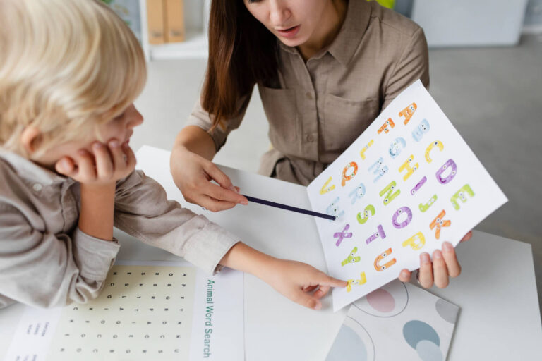 Criança aponta para letras coloridas do alfabeto em avaliação com especialista. Tratamento para dislexia infantil na Clínica Psicokids ABC.